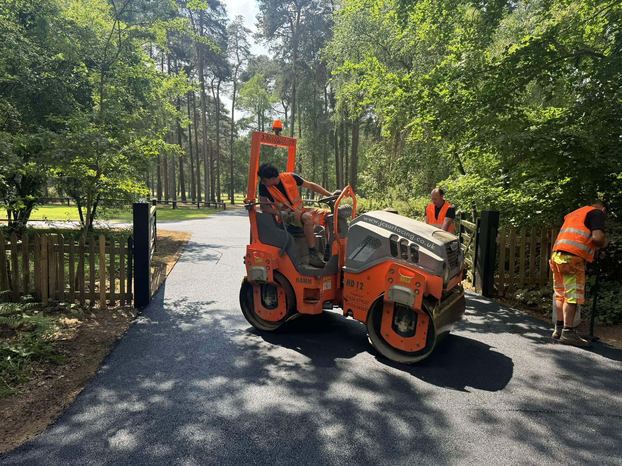 JC Surfacing roller compacting new tarmac driveway in forest area JC Surfacing roller compacting new tarmac driveway in forest area