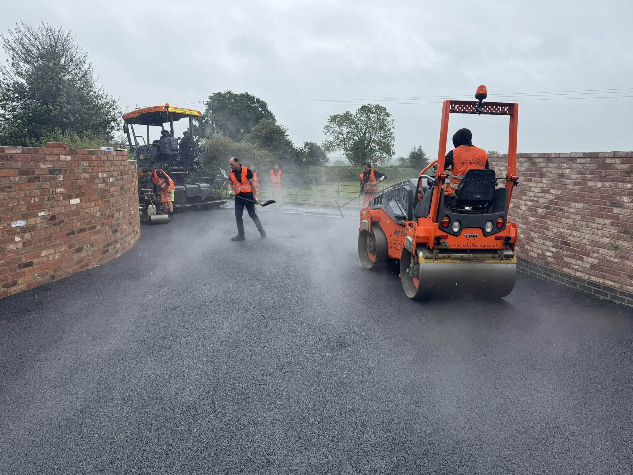 JC Surfacing crew paving curved driveway with fresh asphalt JC Surfacing crew paving curved driveway with fresh asphalt