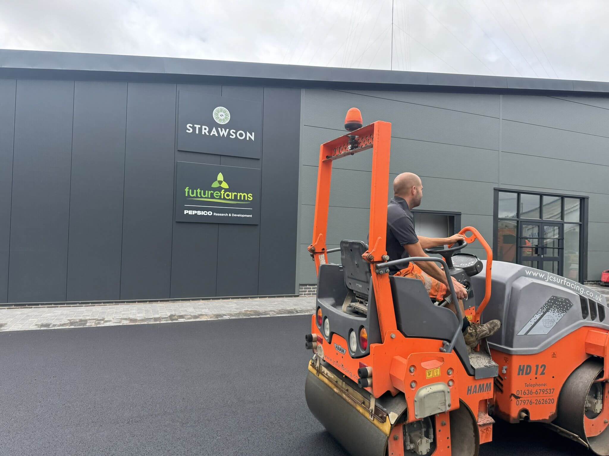 JC Surfacing roller compacting fresh tarmac at commercial site JC Surfacing roller compacting fresh tarmac at commercial site